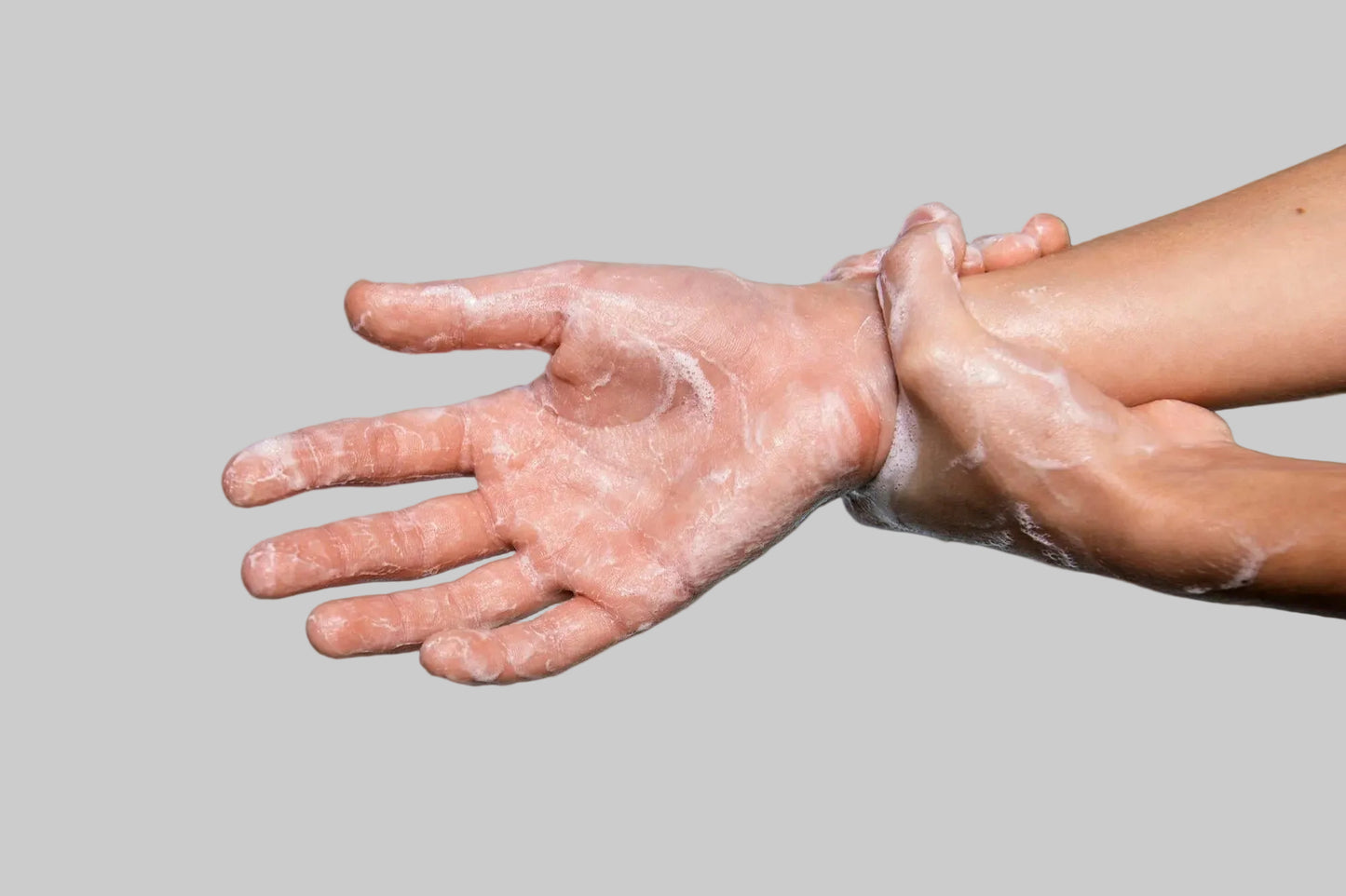 Hands with soap suds against a light blue background