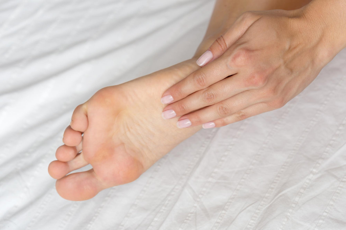 Close-up of a foot and hand on a white background